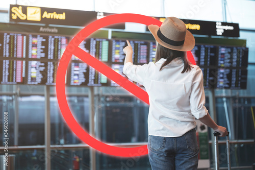 Stop travel in virus outbreak and trip-cancellation concept, Young woman carrying luggage with ignore icon photo