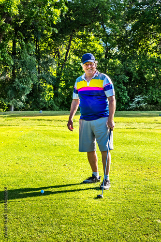 Man teeing off in the tee box, playing golf