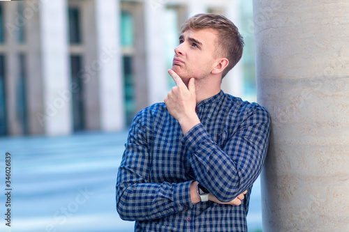 Sad pensive thoughtful guy, young handsome upset frustrated man in shirt thinking about future, idea dreaming or planning outdoors, looking up with hands, arms crossed. Failure, despair concept