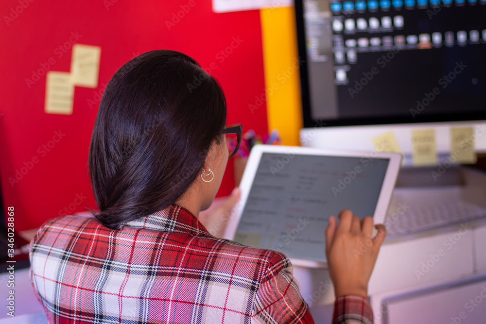 A young woman in suit using a tablet in a colorful office A young woman in suit using a tablet in a colorful office