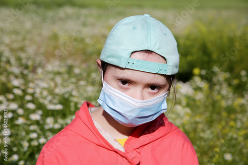 Girl in a mask on her face on background on the flowers field