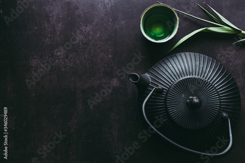 Théière en fonte noire et tasse de thé chaud sur un fond noir photo