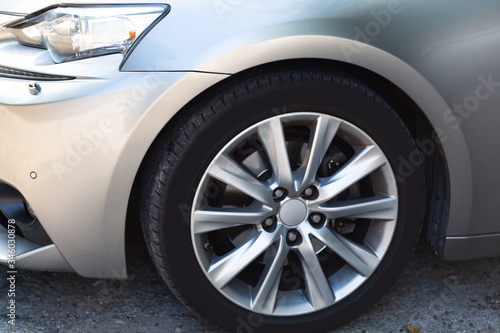 Side view on new luxury car wheel on silver metal rim with black shine tire of a modern luxury technology and auto detail