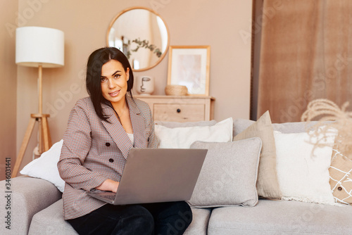 Businesswoman entrepreneur working on laptop from home sitting on the sofa