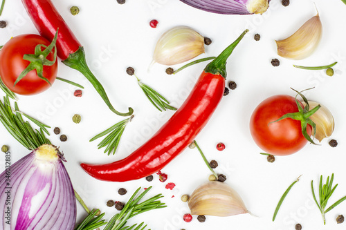 Top view of summer vegetables: onion, garlic, tomato, red pepper, rosemary and peppercorns on white table background.
