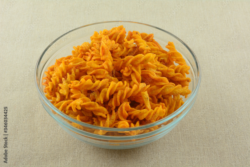 Snack of barbecue flavored corn snacks in twisted sticks in glass bowl