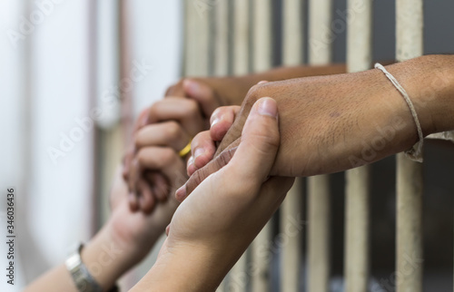 Fotobehang Woman holding the hand of a male prisoner in a white cage.