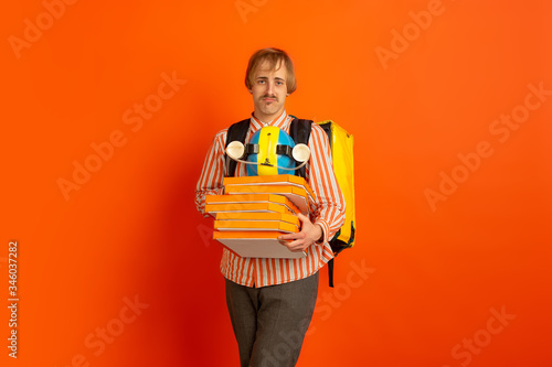 Pizza with love to client. Emotions of caucasian deliveryman isolated on orange background. Contacless delivery service during quarantine. Man delivers food during isolation. Safety. Hurrying up. photo