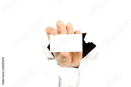 man hand holding white business card thru hole in wall or broken white paper. mockup photo