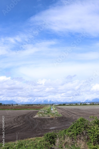 Blue sky cuts  through the white clouds over the farmland with city in the distance