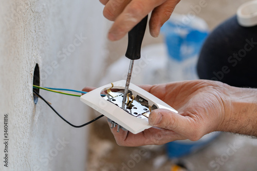 Foto Close up on hands of caucasian man electrician holding screwdriver working on th