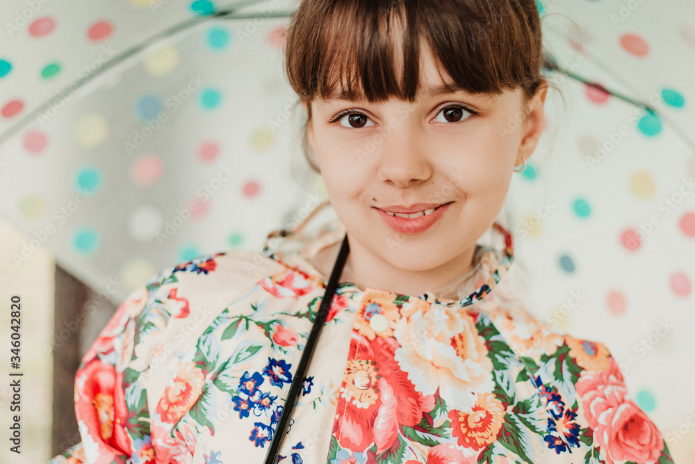A beautiful girl in a bright raincoat walks during the rain under an umbrella. Soft focus A beautiful girl in a bright raincoat walks during the rain under an umbrella. Soft focus