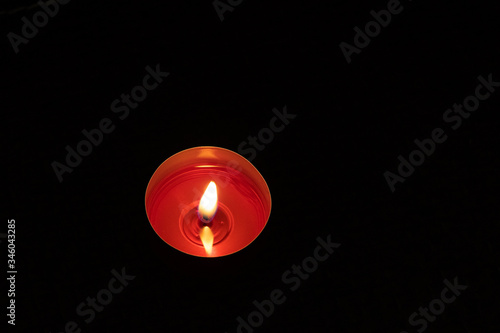 Single candle up close background. Burning red candle on a black background.