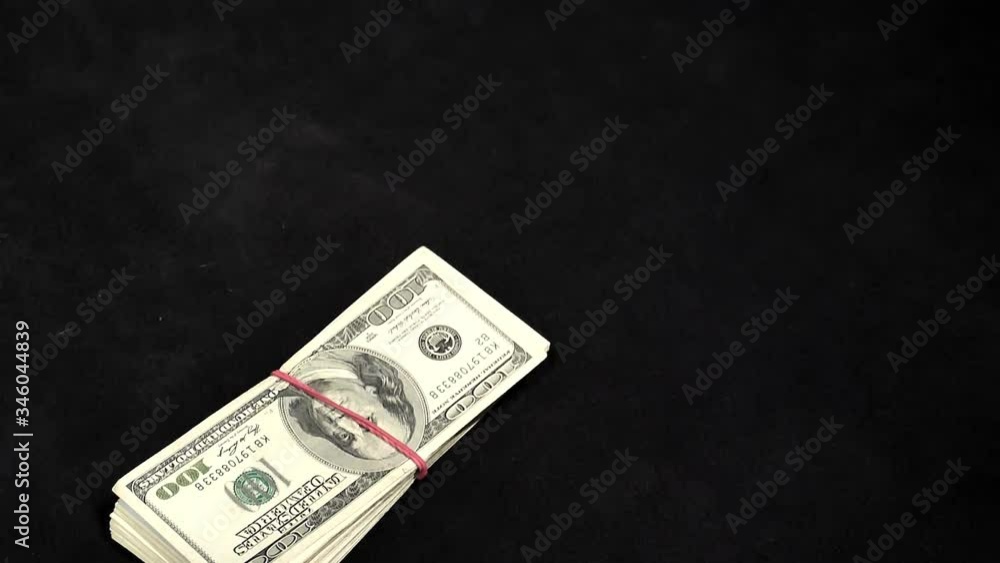 One hundred dollar bundles of notes fall on the table in slow motion. One hundred dollar bundles of notes fall on the table in slow motion.