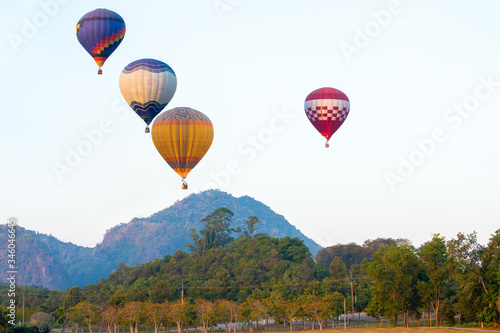 beautiful Hot air balloon  view on colorful sunset background above trees next to the mountains.. © nopporn