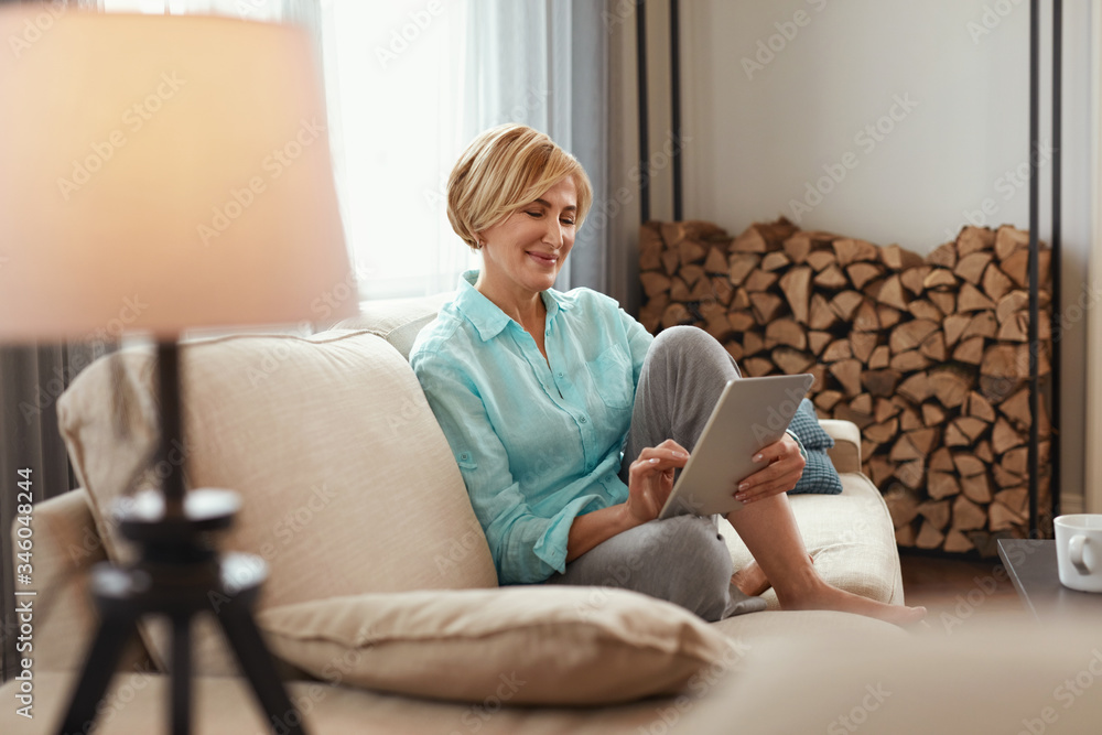 Female With Tablet. Mature Woman On Sofa In Beige Plaid Uses Digital Device Touchscreen, Comfortable Internet Search. High Resolution. Female With Tablet. Mature Woman On Sofa In Beige Plaid Uses Digital Device Touchscreen, Comfortable Internet Search. High Resolution.