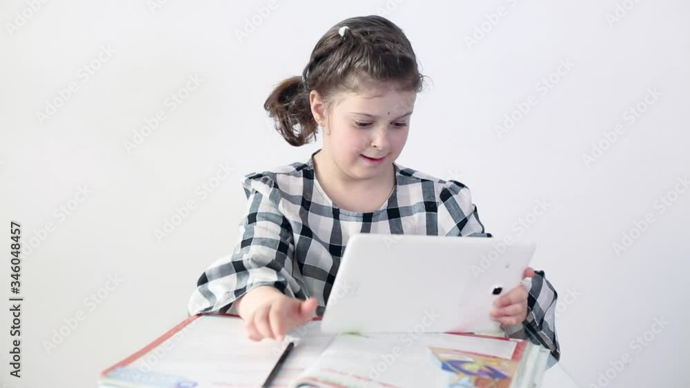 Caucasian teenage girl holding a tablet in her hands and doing homework.Distance Learning Online Education Caucasian teenage girl holding a tablet in her hands and doing homework.Distance Learning Online Education