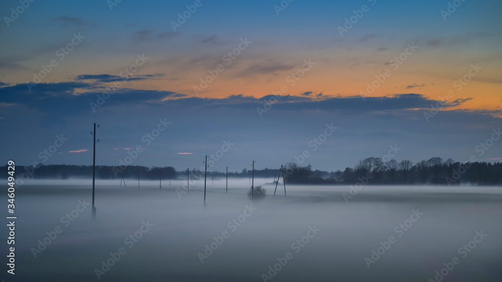 Fog layers over agricultural field during spring sunset (high ISO image)