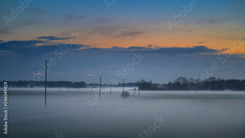 Fog layers over agricultural field during spring sunset (high ISO image)