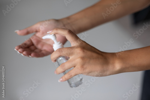 Close up view of woman person using small portable antibacterial hand sanitizer on hands