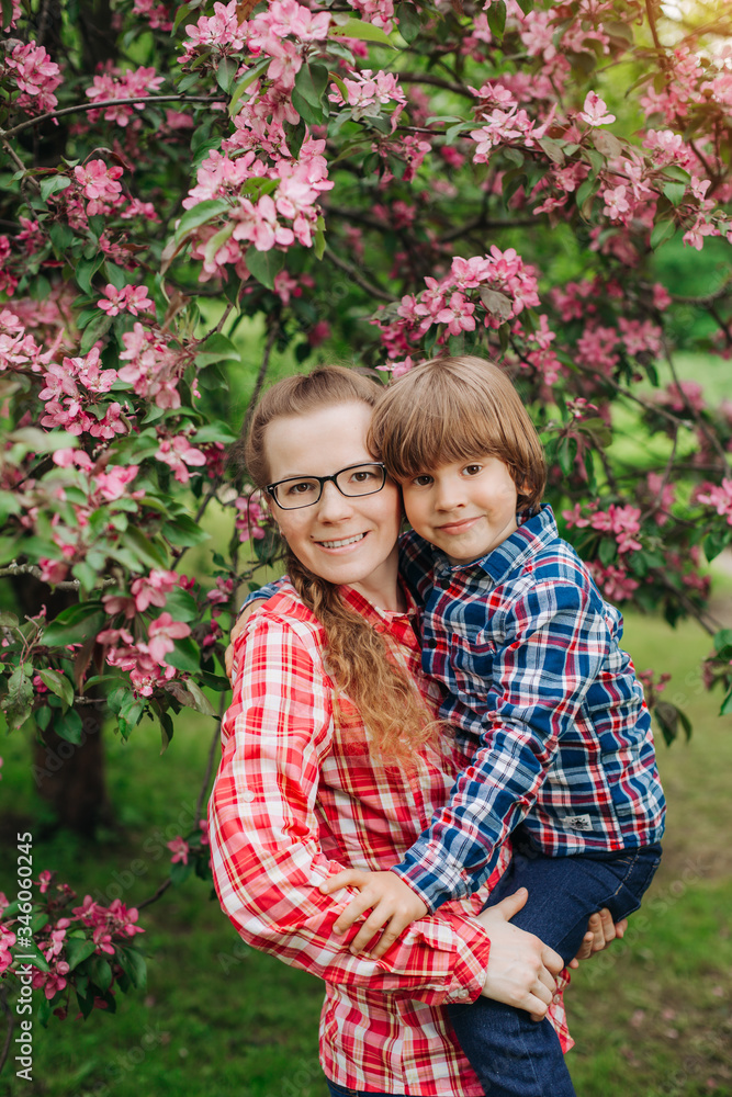 Mother and baby in blooming garden. Mom and child in spring. Springtime family scene. Flowers of apple or cherry tree. Mother and baby in blooming garden. Mom and child in spring. Springtime family scene. Flowers of apple or cherry tree.