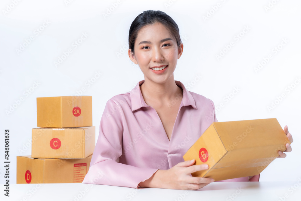 Asia woman freelancer working and checklist and writing order with cardboard box on bed at home Asia woman freelancer working and checklist and writing order with cardboard box on bed at home