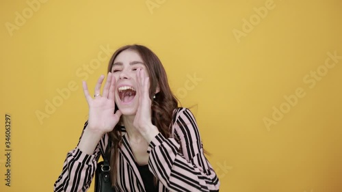 Cute Young Woman With Bag Light Brown In Striped Pink, Black Shirt On A Yellow Background, Cheerful Girl Talking Loudly Or Shouting, Holding Her Hand Near Mouth. Concept Of Communication, Information