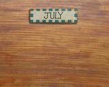 Vintage calendar  handmade from wood on wooden wall, on July of the year.