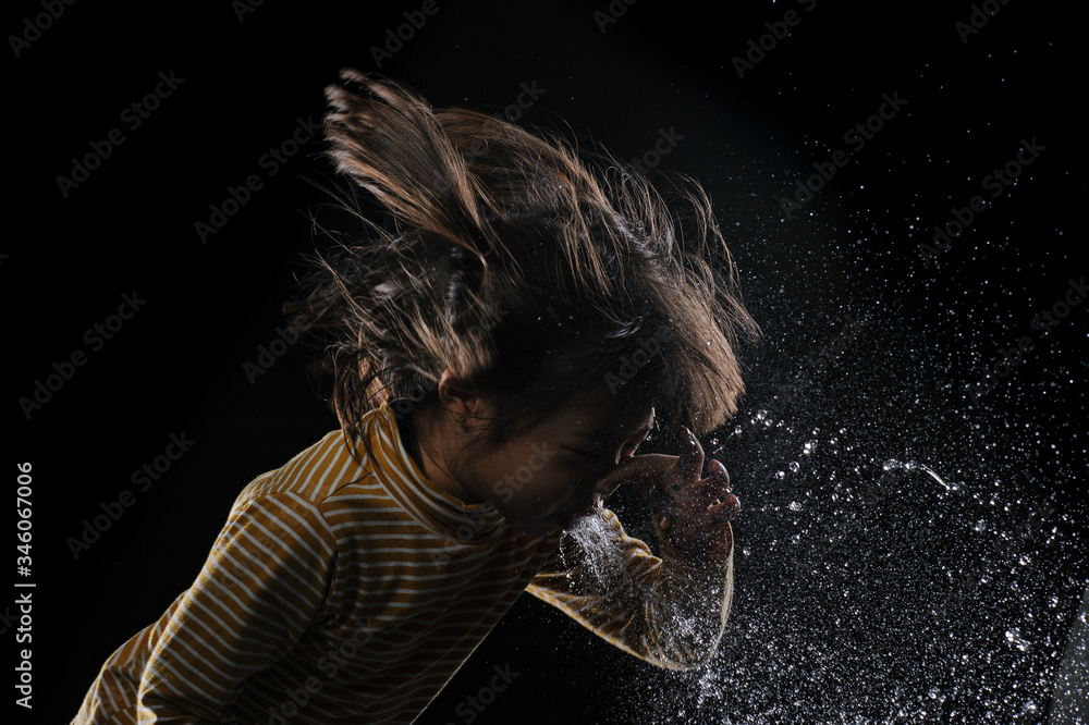 Fototapeta Kid of sneezing, coughing, shocking food concept. A little Asian girl of 5 years old covered nose while sneezing and Causing the water to flow out of the mouth with black background.