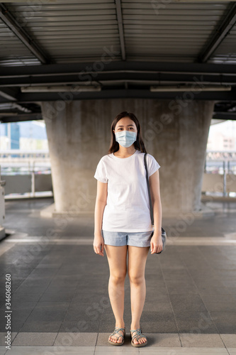 Beautiful young Asian woman wearing the protective mask while traveling in the city where fully with air pollution pm2.5. Unhealthy urban air pollution problem and coronavirus disease in Asia.