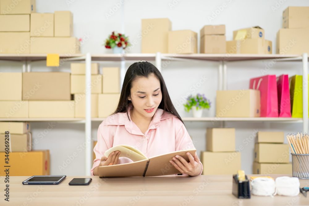 Young Asian business woman packing a post boxes to be shipped to customers. Ecommerce online shopping concept. Expertise online sales person packing customers parcel boxes for shipment. Young Asian business woman packing a post boxes to be shipped to customers. Ecommerce online shopping concept. Expertise online sales person packing customers parcel boxes for shipment.