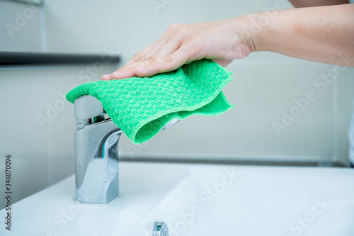 Bild auf Leinwand Woman house keeper cleaning a dirty stainless water tap on the wash basin in toilet