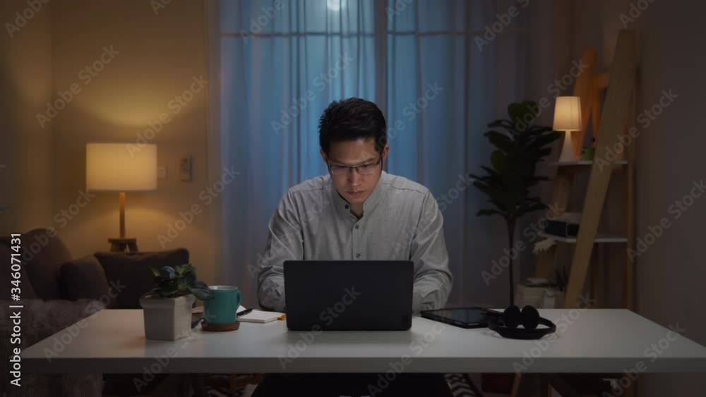 Portrait of asian man and serious millennial hard working at home,thinking and feeling thoughtful.Working from Home overload at night, self isolation in new normal concept.Working late and Overtime Portrait of asian man and serious millennial hard working at home,thinking and feeling thoughtful.Working from Home overload at night, self isolation in new normal concept.Working late and Overtime