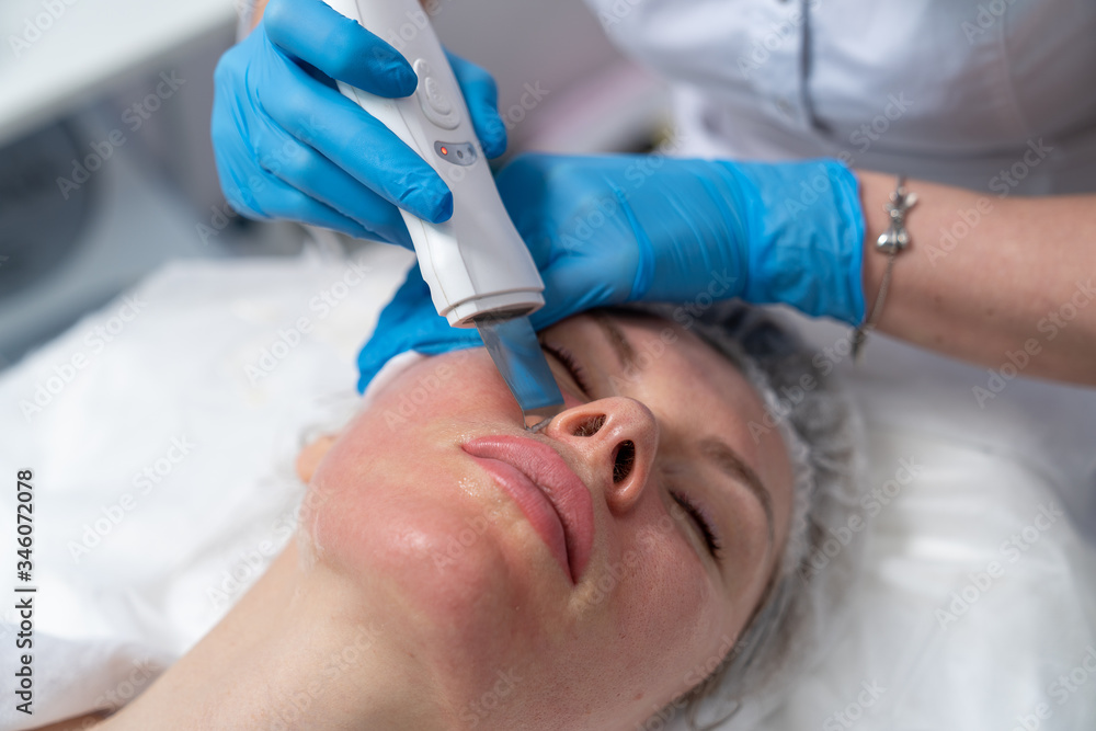 Beautician does facial skin cleansing for his client. Cleansing the skin with special tools. Facial cleansing mask. Beautician does facial skin cleansing for his client. Cleansing the skin with special tools. Facial cleansing mask.