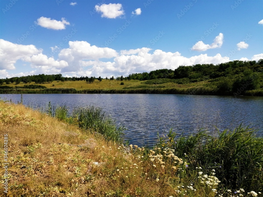 Beautiful summer landscape of a wide lake between hills under a blue sky.