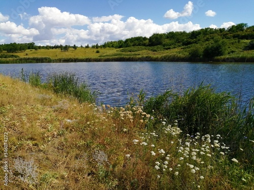 A wide caim river or lake between hills with grass and trees. photo