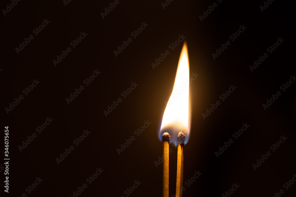 Couple of matches burning together with heat flame isolated on a black background Couple of matches burning together with heat flame isolated on a black background