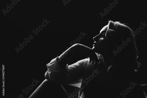 Silhouette of a beautiful young blonde woman in low key. Black and white art photo. Soft selective focus.