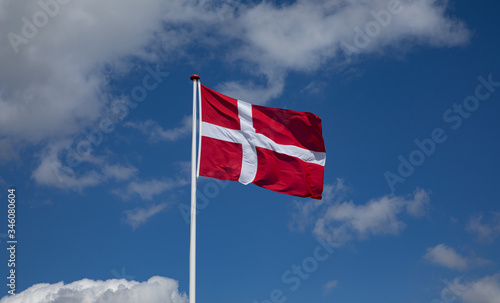danish flag in the wind with blue sky and clouds
