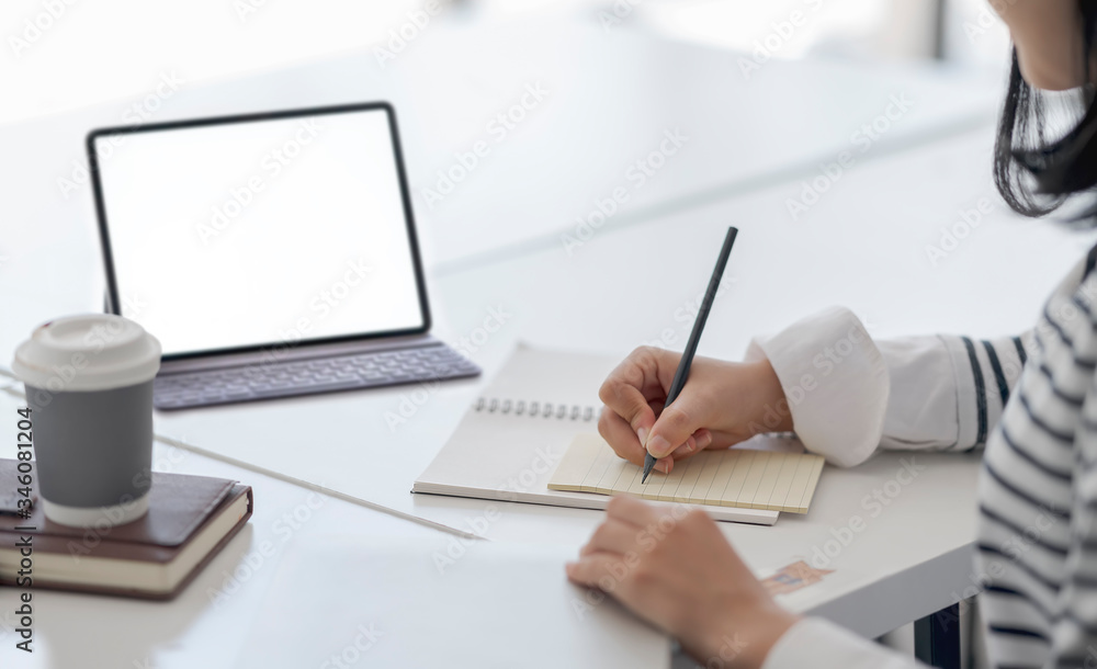 young asian woman using pencil writing on diary blank page while sitting at home office.