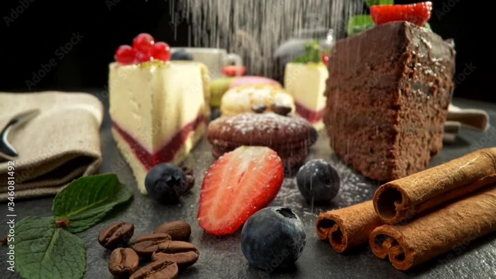 Various cakes, strawberries, blueberries, and redcurrant are being powdered with icing sugar like snowfall from above. Slider shot, slow motion Various cakes, strawberries, blueberries, and redcurrant are being powdered with icing sugar like snowfall from above. Slider shot, slow motion