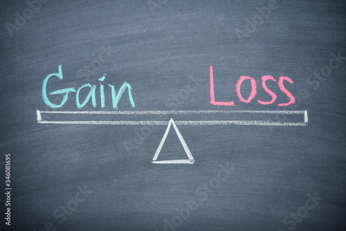 Text word gain and loss balance on seesaw drawing writing on chalkboard or blackboard background. Concept of gain and loss analysis in business, financial management and investment.