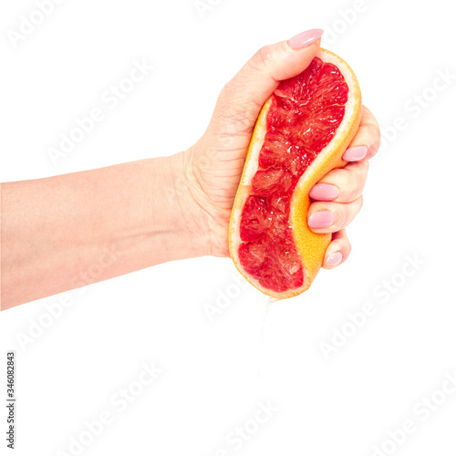 The female hand squeezes out juice from a ripe grapefruit. Isolation on white.