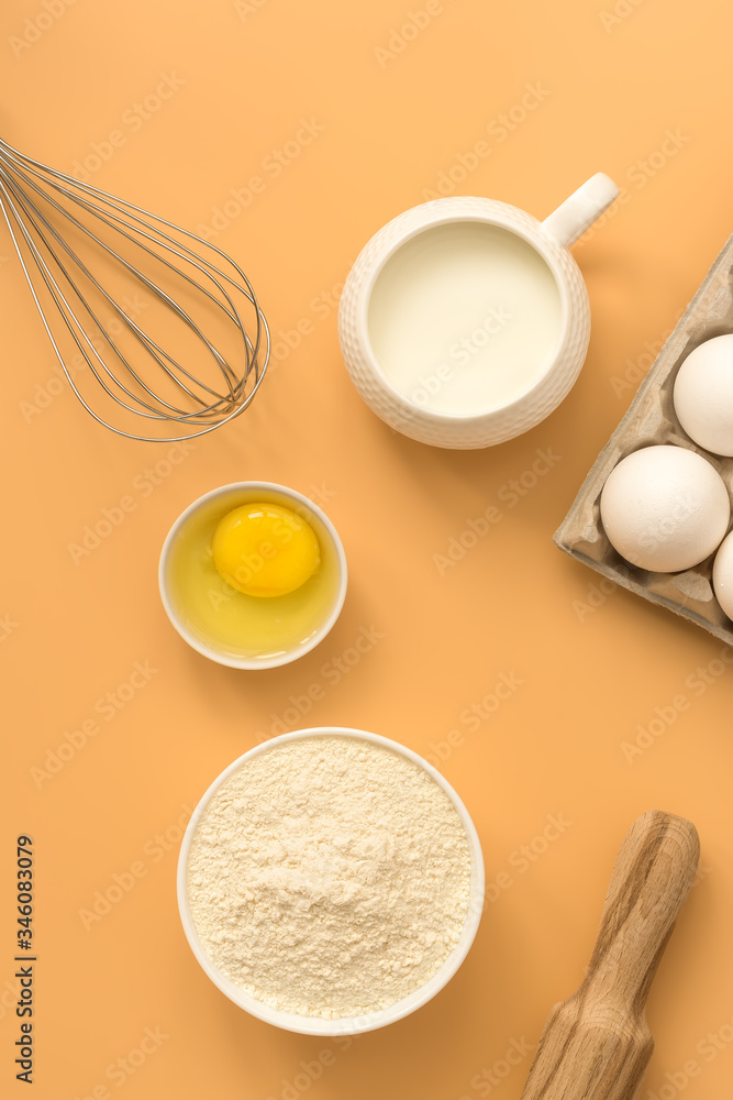 Baking background. Flour, eggs, milk, whisk and rolling pin on a pastel yellow background. Top view, flat lay Baking background. Flour, eggs, milk, whisk and rolling pin on a pastel yellow background. Top view, flat lay