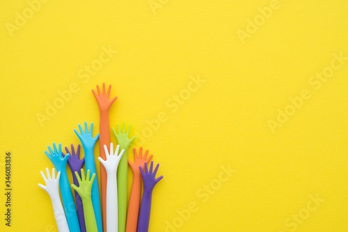 Many colorful hands up on yellow background with copy space. Concept of international human rights, equality and peace. Color hands are symbol of diversity. photo