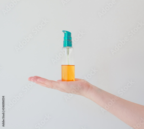 Girl holds cosmetic oil in blank vial blank with pump. Sea buckthorn oil for the treatment and rejuvenation of the skin
