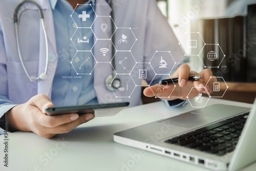 Medical Technology Concepts The doctor is working on a tablet and audio player and a digital tablet computer in a modern office in the morning at the desk.