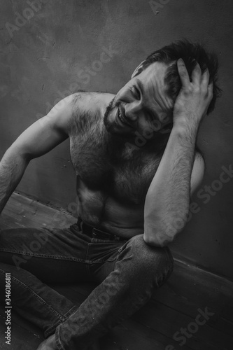 Cute shirtless man sitting on the floor. Black and white low-key studio portrait. photo