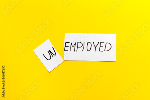 Unemployed - employed - torn paper sheet on yellow background top view. Hiring concept.
