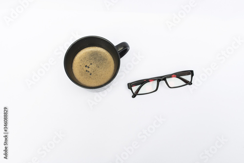 Eyeglasses and cup on white background